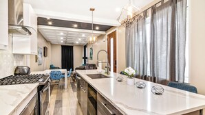 Una cocina moderna con una isla central, electrodomésticos de acero inoxidable y una zona de comedor con sillas azules.