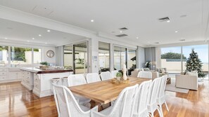 Cozy dining area with a wooden table and wicker chairs, kitchen with white cabinetry and a large island, and a comfortable seating area.
