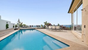 Relax by the ocean-view pool surrounded by lush greenery and comfortable lounge seating.