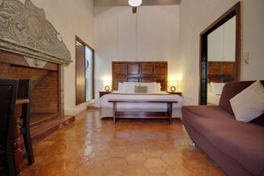 A bedroom with a large bed, a wooden headboard, a bench, and a sofa.