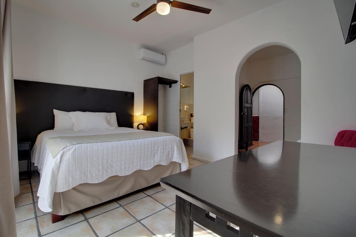 Une chambre à coucher avec un lit, un bureau et un ventilateur de plafond.