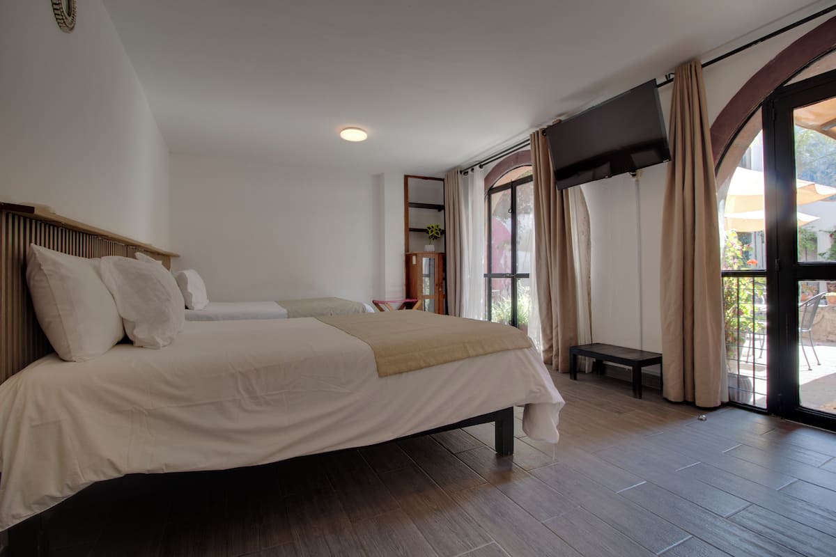 Une chambre avec un grand lit, une télévision et une vue sur l’extérieur.