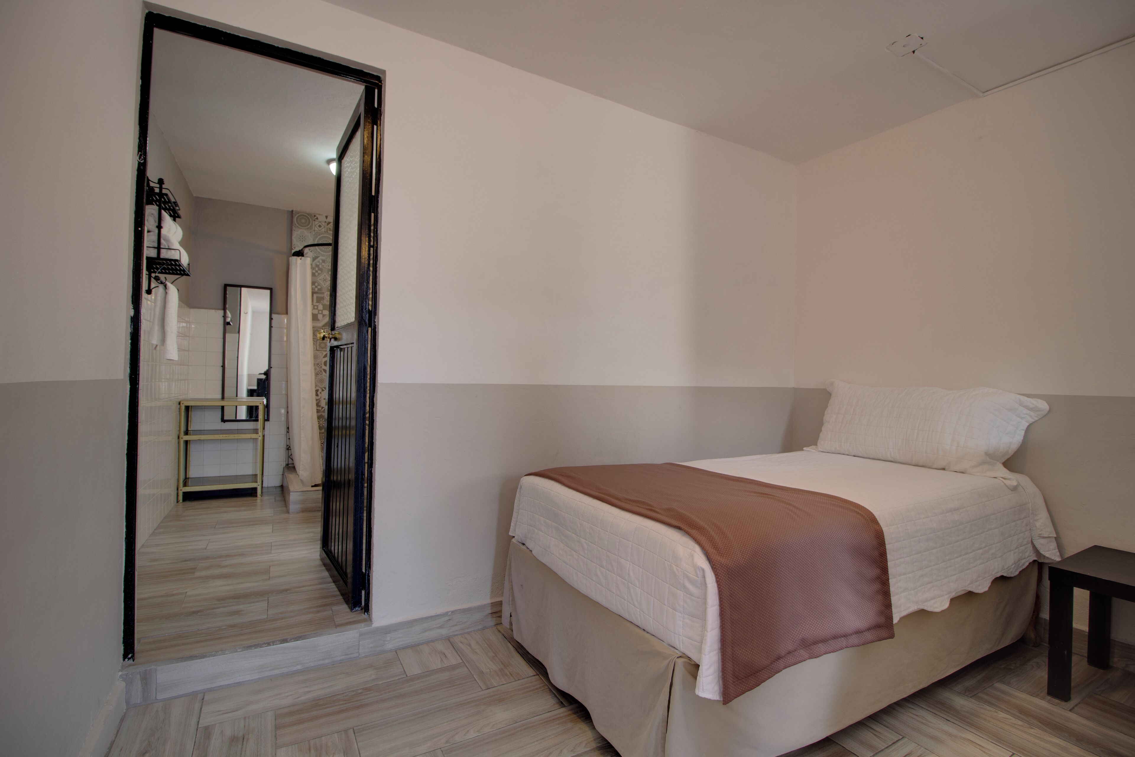 Un dormitorio con una cama, una mesita de noche y una puerta que da a un baño.