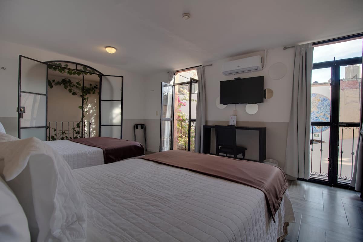 Une chambre d’hôtel avec deux lits, un bureau, une télévision et une grande fenêtre.