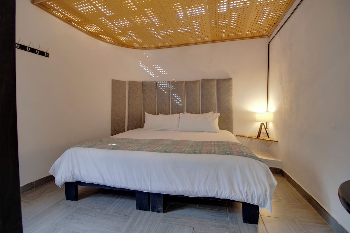 Une chambre à coucher moderne avec un grand lit, un luminaire au plafond et une étagère fixée au mur.