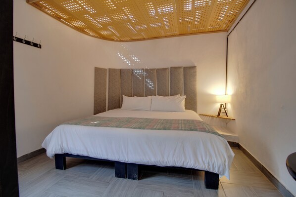 Une chambre à coucher moderne avec un grand lit, un luminaire au plafond et une étagère fixée au mur.