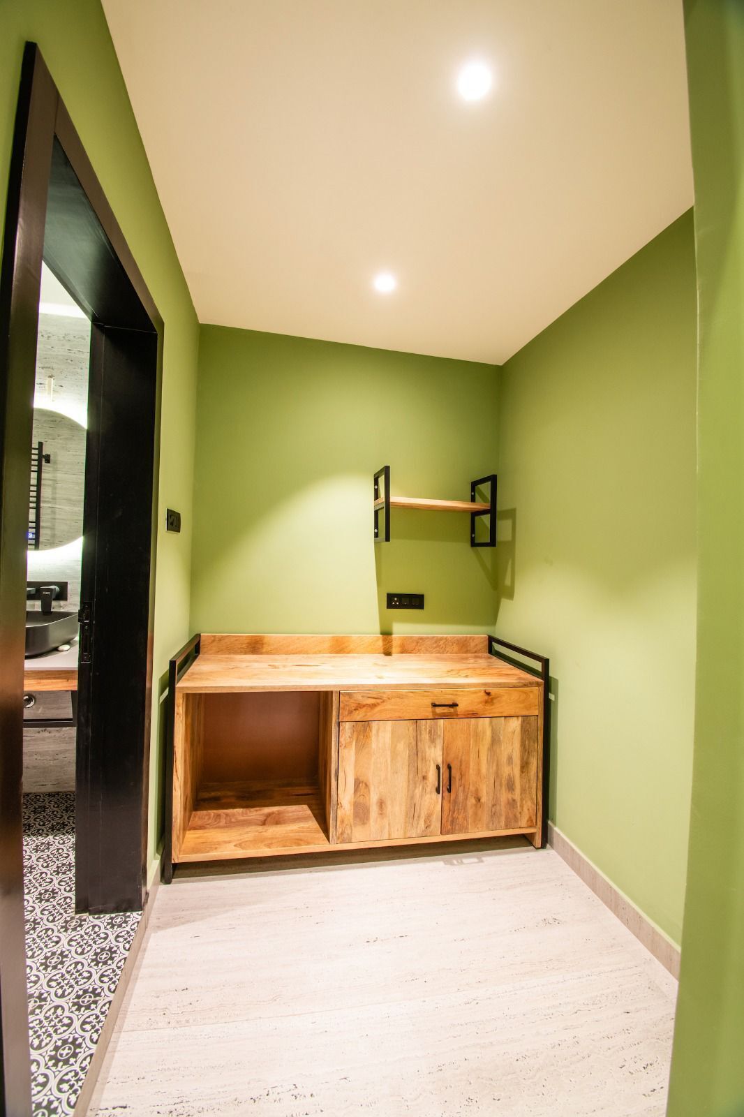 A room with a wooden bench, a mirror, and a light fixture on the ceiling.