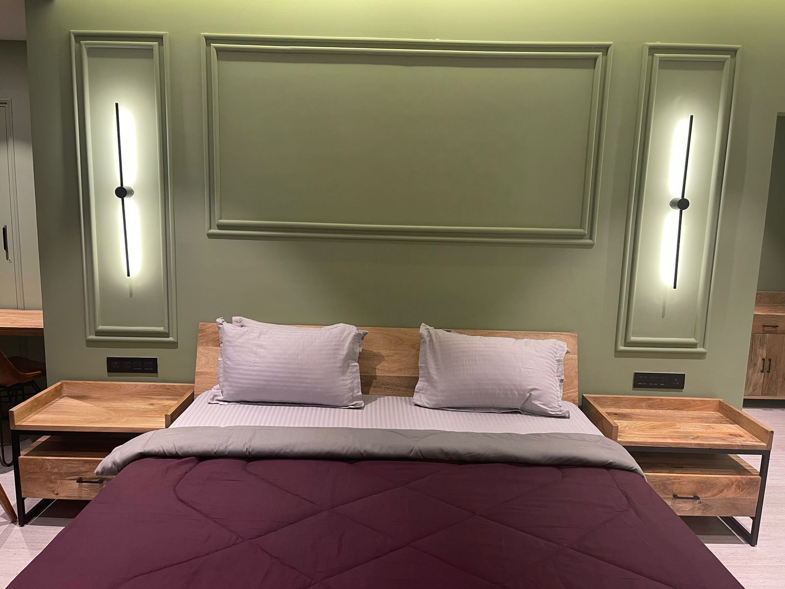 A bedroom with a large bed, two bedside tables, and wall-mounted lighting.