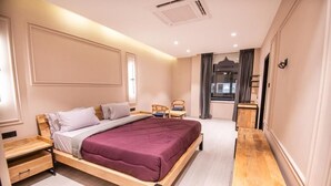 Une chambre moderne avec un lit en bois, des tables de chevet, un petit coin salon et une vue sur l’extérieur.