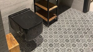 Une salle de bain moderne avec un lavabo rectangulaire, un miroir rond avec un éclairage intégré et des toilettes.