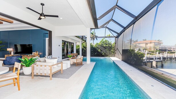 Ein moderner Poolbereich im Innenbereich mit freiem Blick auf den Pool, einem Deckenventilator und einer Sitzecke mit Fernseher.