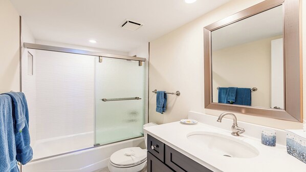 A modern bathroom with a glass-enclosed shower, a large mirror, and a white sink. - Beachfront Bliss: A Perfect Getaway. (Marco Island)