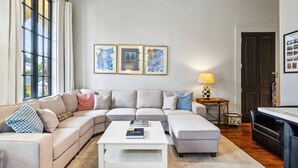 A living room with a sectional sofa, a coffee table, and framed artwork on the wall. - The Retreat off Magazine (New Orleans)