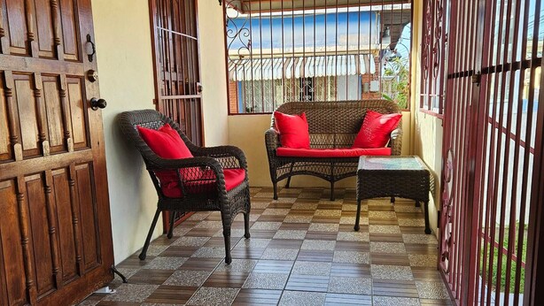 Un espacio de estar al aire libre cubierto con mobiliario de mimbre y suelo a cuadros.