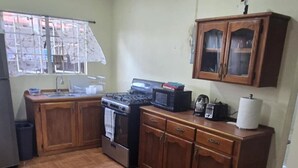 Una cocina con armarios de madera, una estufa, un microondas y un ventanal con vistas al exterior.