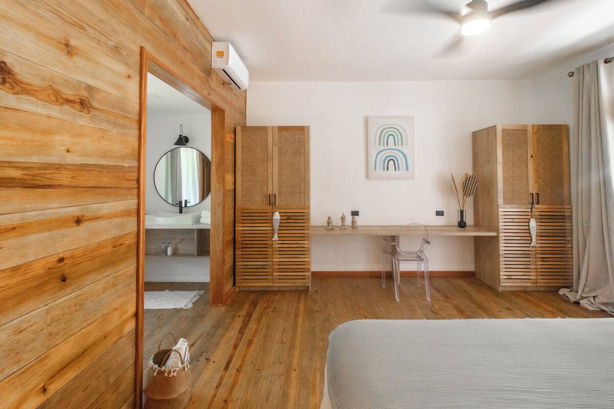A bedroom with wooden walls, a bed, a desk, and a wardrobe.