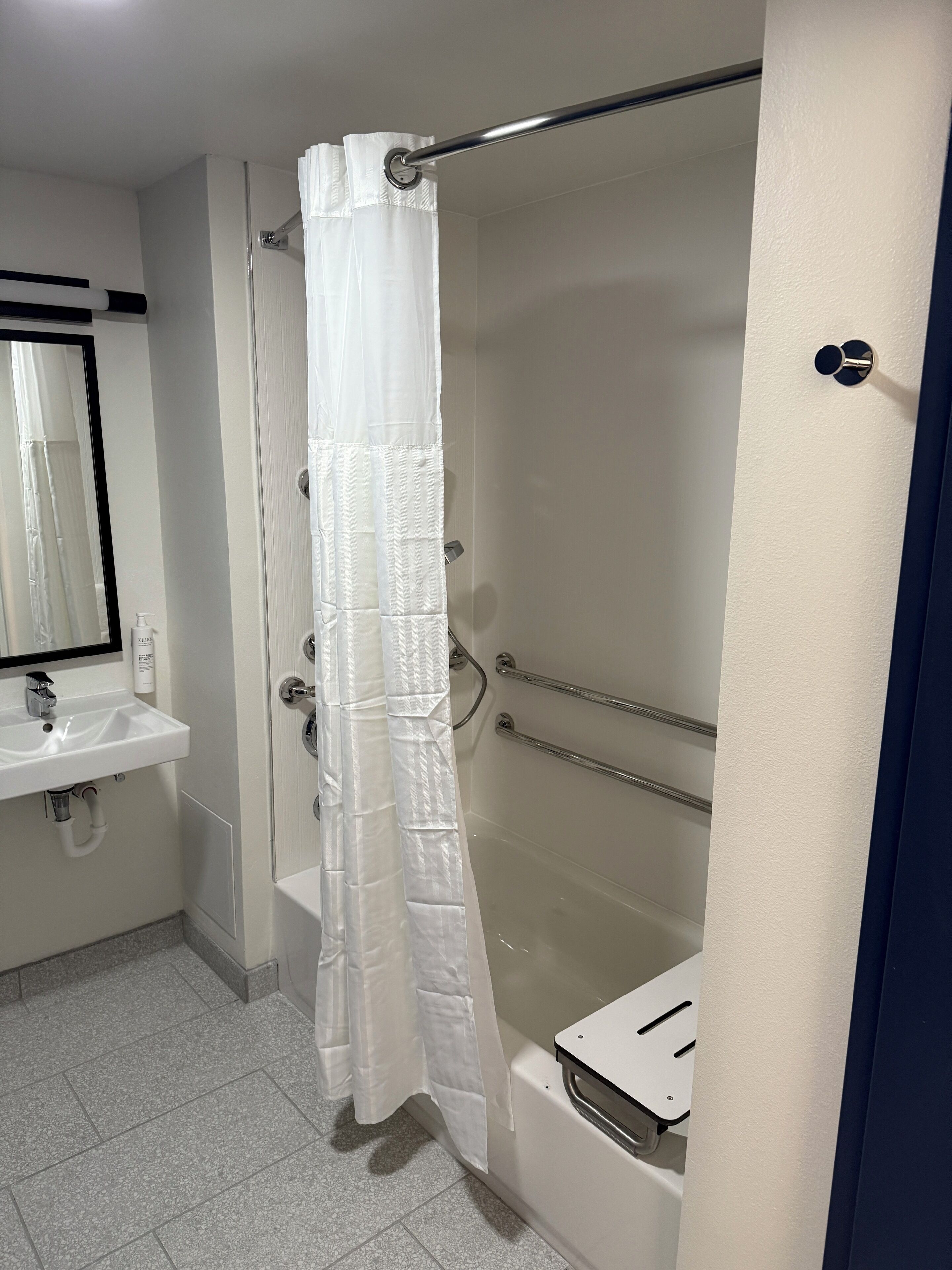 Baño con lavamanos blanco, espejo y cortina de ducha.