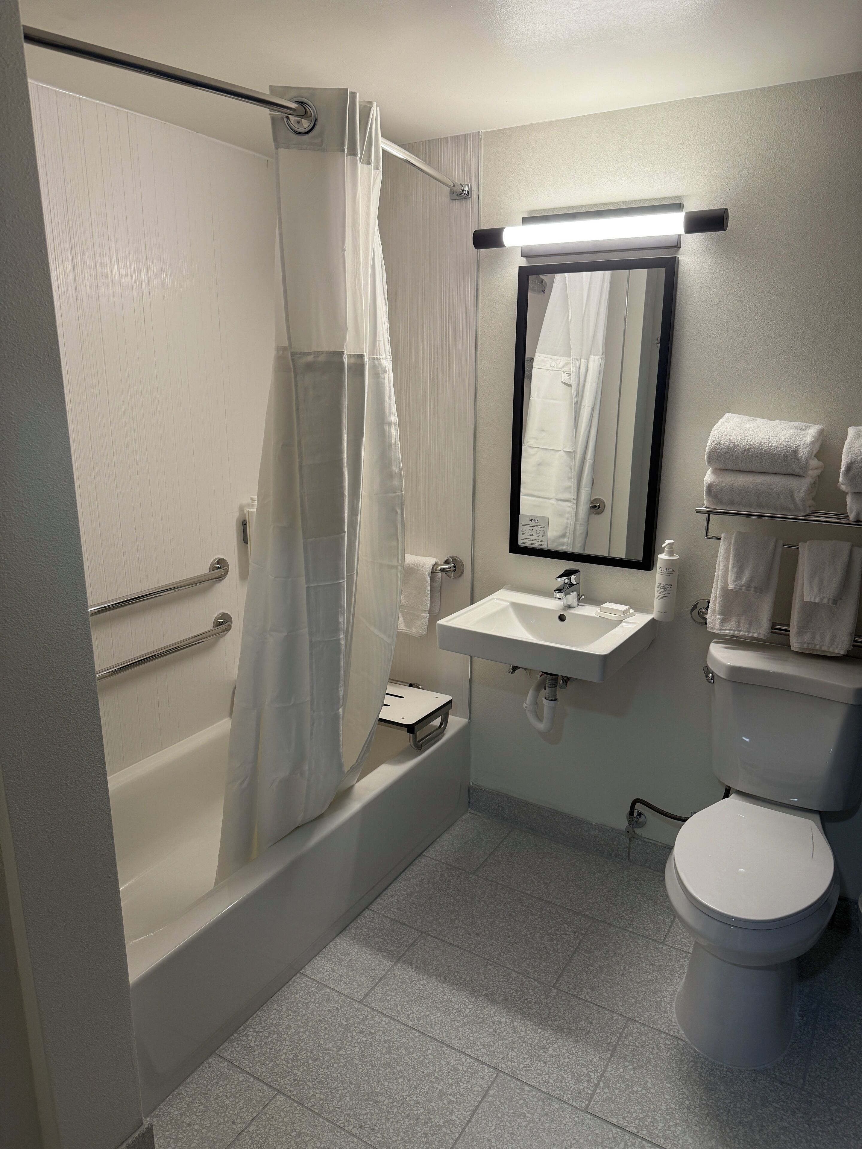 A bathroom with a bathtub, a shower curtain, a sink, a mirror, and a toilet.