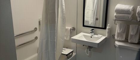 A bathroom with a bathtub, a shower curtain, a sink, a mirror, and a toilet.