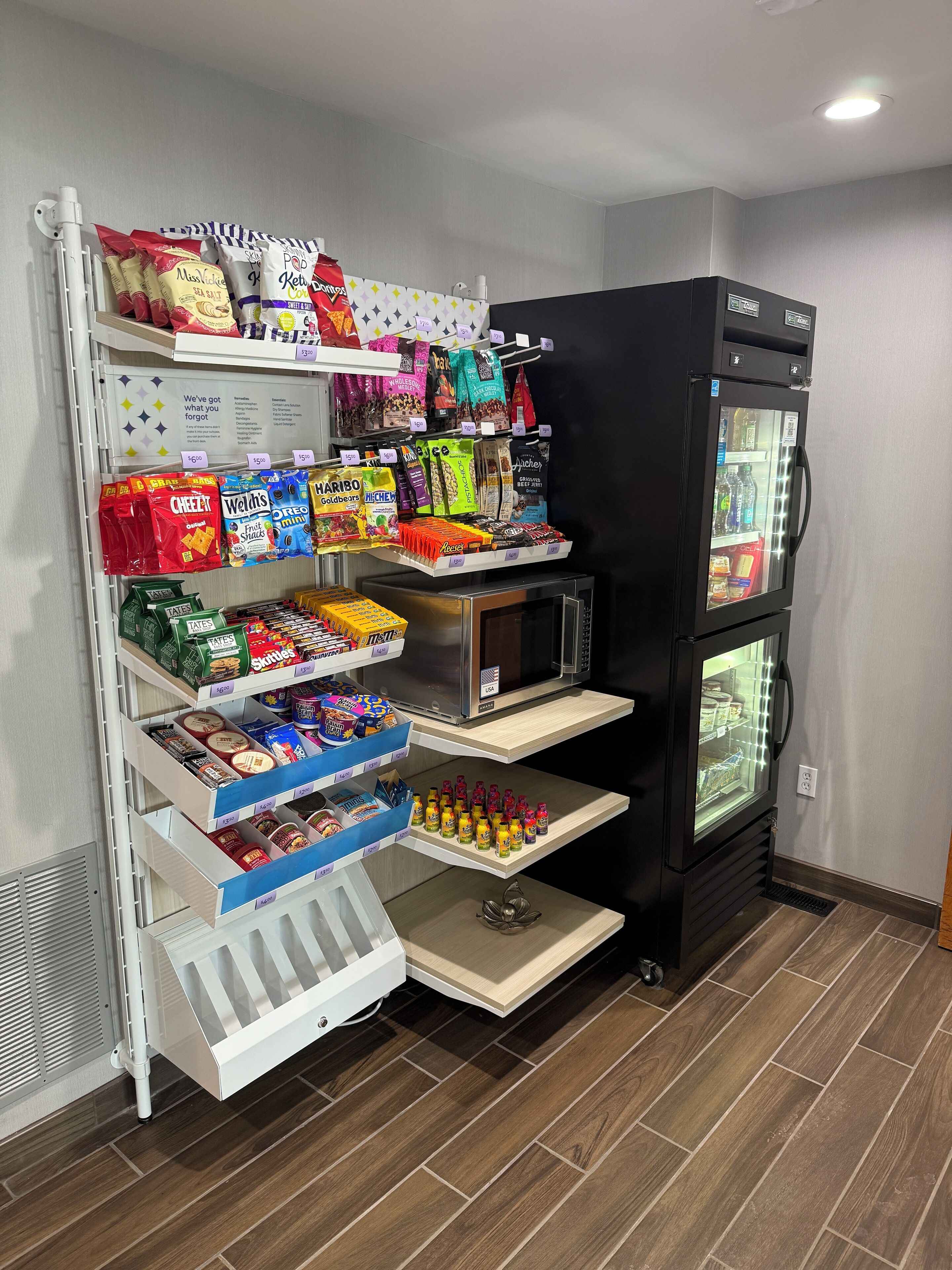 A vending machine stocked with snacks and beverages, a microwave, and a refrigerator.