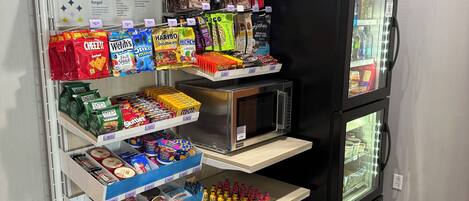 A vending machine stocked with snacks and beverages, a microwave, and a refrigerator.