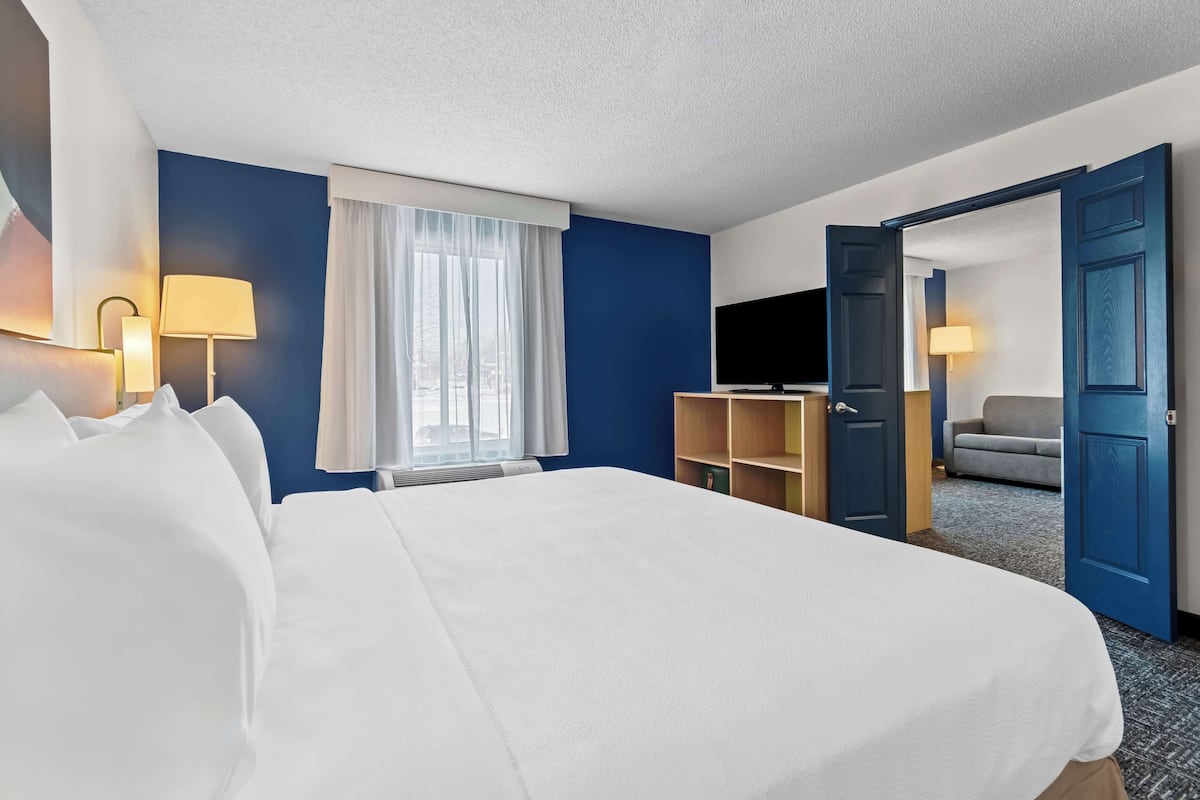 A hotel room with a large bed, a TV, a desk, and a chair.