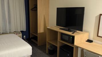 A hotel room with two beds, a TV, a desk with a computer, a microwave, and a wardrobe.