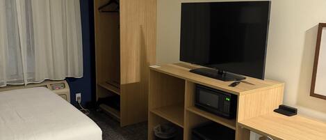 Ett hotellrum med två sängar, en TV, ett skrivbord med en dator, en mikrovågsugn och en garderob.