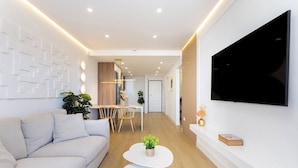 A modern living room with a sofa, a dining area, and a TV mounted on the wall. - Home2Book Costa Adeje Escape & Pool, Only Adults (Adeje)