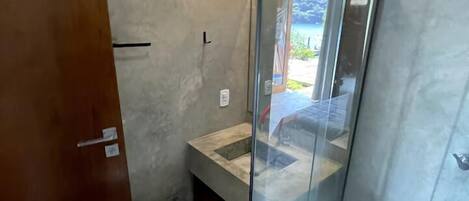 Un baño con cabina de ducha de vidrio, puerta de madera y un ventanal pequeño.