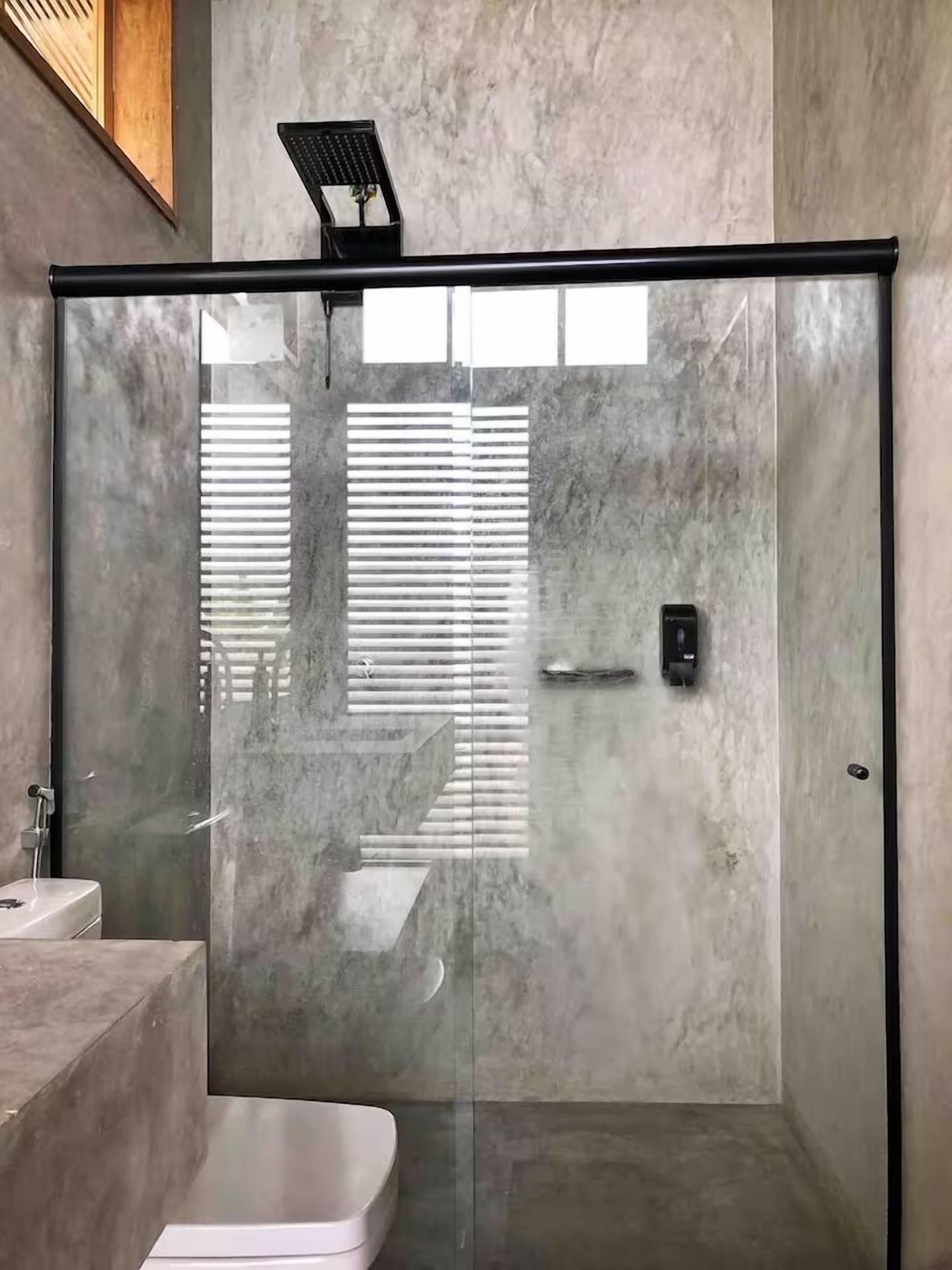 Uma casa de banho moderna com cabine de chuveiro em vidro, lavatório de mármore e sanita.