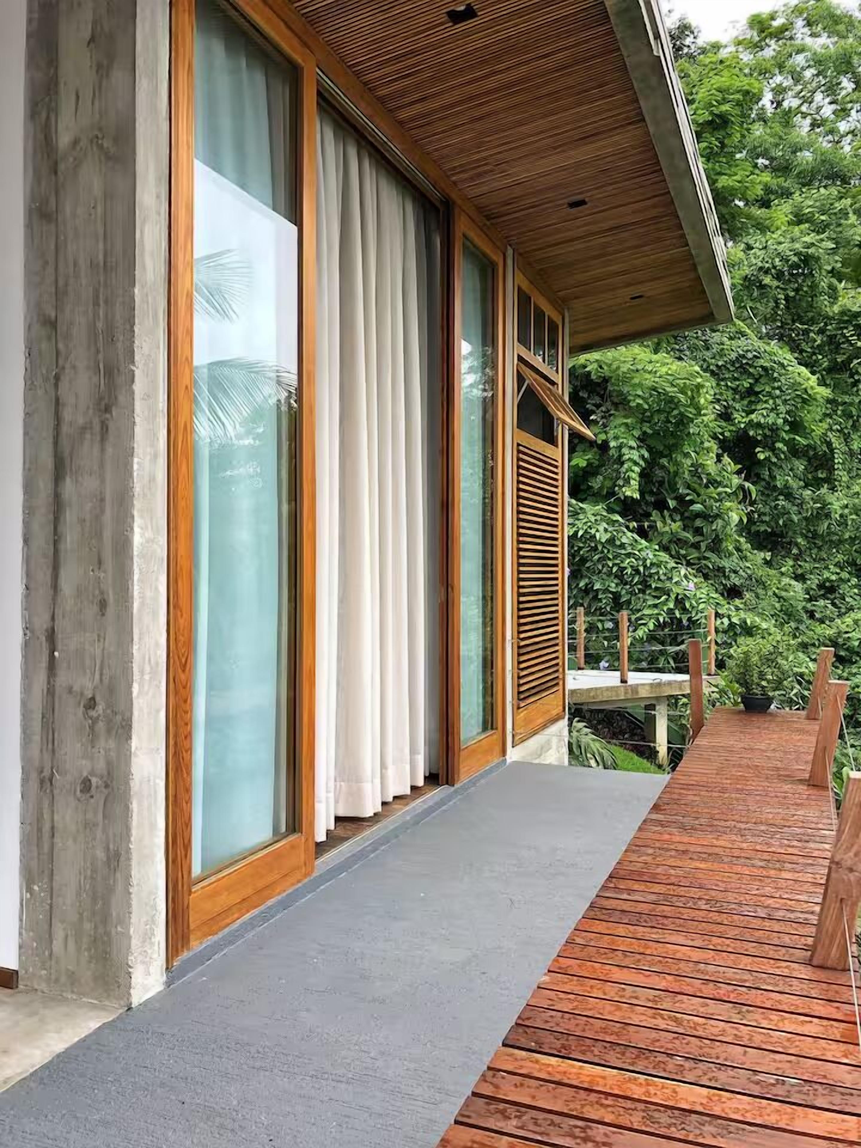A wooden deck with a glass door leading to a covered area.