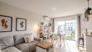 Una sala de estar moderna con un sofá seccional gris, una mesa de centro de madera y un estante blanco con plantas.