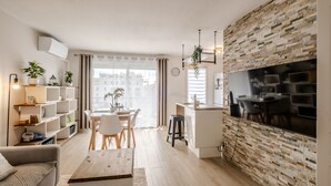 Una sala de estar moderna con comedor, una cocina con televisor grande y vistas a la ciudad.