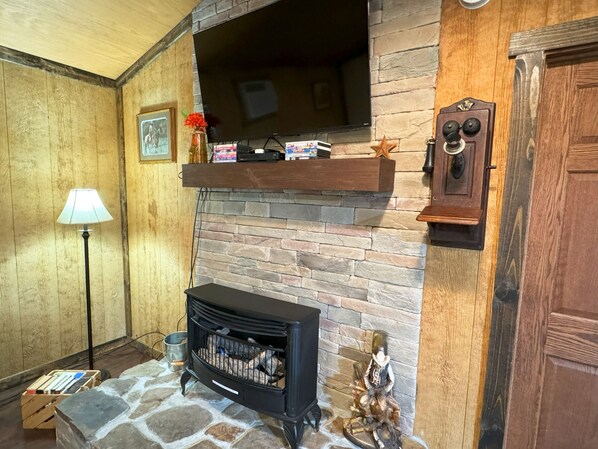A cozy living room with a stone fireplace, a mounted television, and a wooden door.