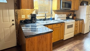 A kitchen with wooden cabinets, a microwave, a stove, and a coffee maker.