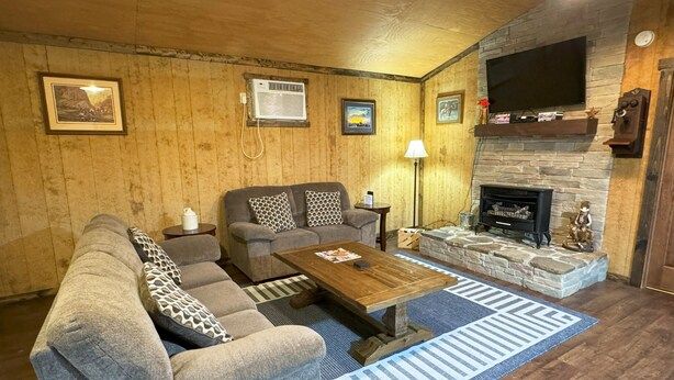A cozy living room with a sofa, armchairs, a coffee table, and a fireplace.