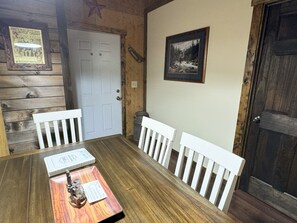 Un tavolo da pranzo in legno con sedie bianche, un quadro appeso al muro e una porta decorata con una stella.