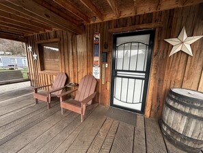 A wooden porch with Adirondack chairs, a welcome sign, and a barrel.