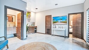 Un hall d’hôtel moderne doté d’un coin cuisine, d’un téléviseur à écran plat et d’un espace repas.