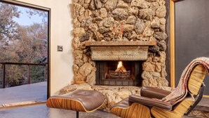 A modern living room with a stone fireplace, leather armchairs, and a view of the outdoors. - The Soul of the River  (Three Rivers)
