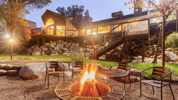 A modern outdoor patio with a fire pit, seating, and a stone wall. - The Soul of the River  (Three Rivers)