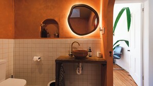 A bathroom with a wooden sink, a round mirror, and a white toilet.