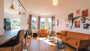 A modern living room with a wooden floor, a sofa, a coffee table, and a dining area with chairs.