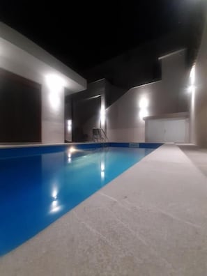 An indoor swimming pool with a clear blue water surface, surrounded by walls with built-in lighting fixtures. - Villa Diamond (Mostar)
