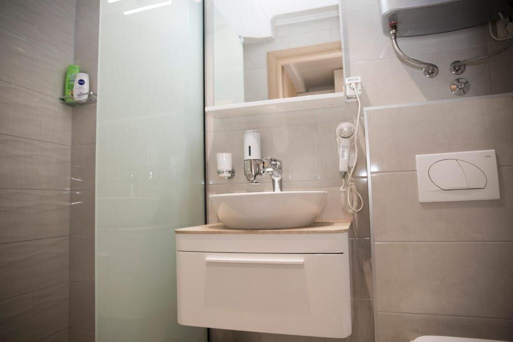 A modern bathroom with a glass shower enclosure, a white sink, and a handheld showerhead.