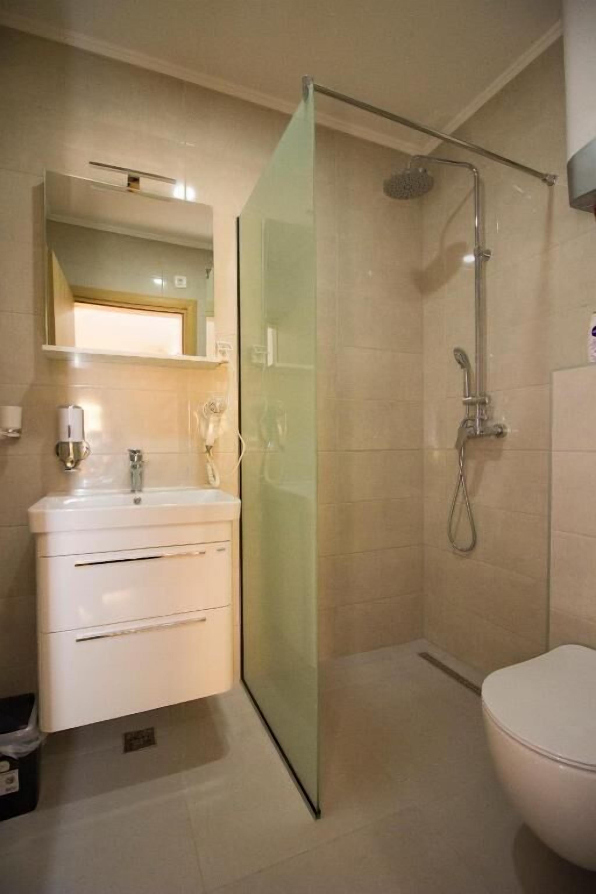 A modern bathroom with a glass shower enclosure, a white sink with a mirror, and a toilet.
