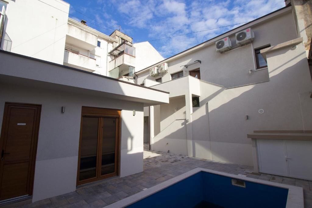 Un edifici modern amb una piscina, una porta de fusta i un petit balcó.
