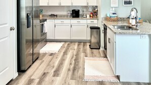 Cocina moderna con armarios blancos, electrodomésticos de acero inoxidable y encimera de granito.