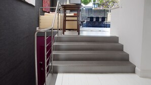 Un escalier avec des rampes en métal mène à un espace de vie comprenant un canapé et une table.